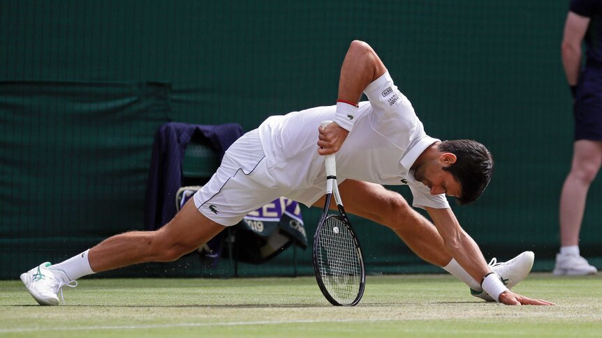 Novak Djokovic 几乎做到了劈叉但靠在这个球拍上以阻止自己进一步跌落